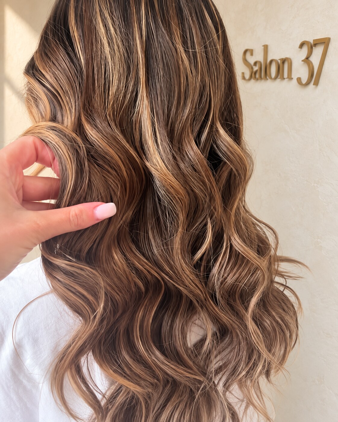 Long brunette hair with soft caramel highlights and loose waves, viewed from the back
