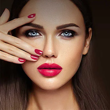 Brunette woman with smoky eye makeup, red lipstick and a red manicure